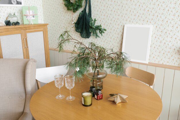 Новогодний декор в гостиной два стакана на столе еловые ветки в вазе