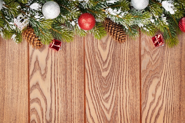 Christmas decor and snow fir tree over wooden background with copy space