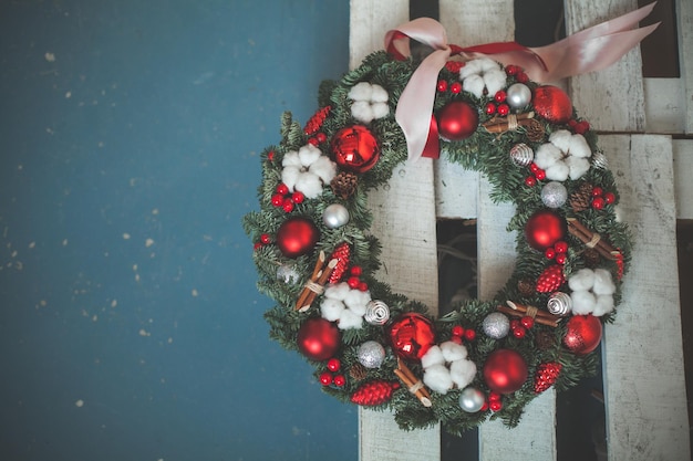 緑のクリスマスツリーの小枝、赤いガラスのボール、リボン、青い背景に新年のホリーベリーとクリスマスの装飾