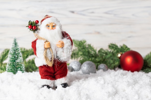 サンタクロースのおもちゃ、モミの木の枝、輝くボール、雪のクリスマスの装飾。
