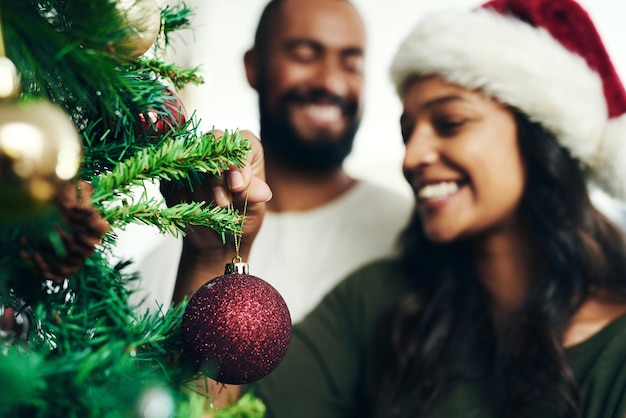Фото Рождественское украшение елки и счастливая черная пара празднуют праздничный сезон любовью, счастьем и праздничной связью черная женщина мужчина улыбается вместе и наслаждается украшением рождественской елки в гостиной
