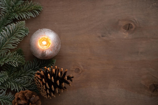 Christmas decoration composition with burning candle cone and lights on natural wooden background