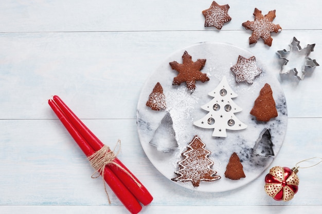 2つの赤いろうそくと砂糖の粉を振りかけたクリスマスの装飾とクッキー