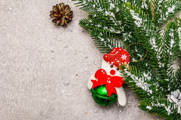 Christmas decoration. Evergreen fir tree branch, cones, snowman and artificial snow.