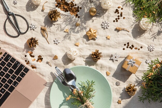 Christmas decoration. Festive plate and cutlery, laptop with Christmas decorations at sunny day. Holiday, New Year , Hard light with shadows