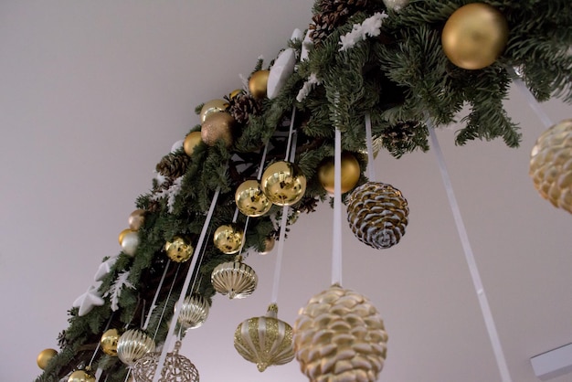 Photo christmas decoration, fir branch with golden festive balls and fir cones hanging on the ceiling