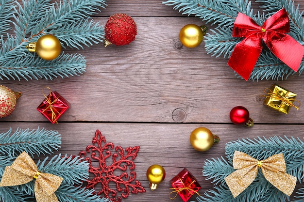 Christmas decoration. Fir-tree branch with balls, snowflake and bows on a grey background