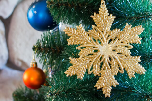 Christmas decoration in the form of a gold snowflakes close up and other toys on the Christmas tree