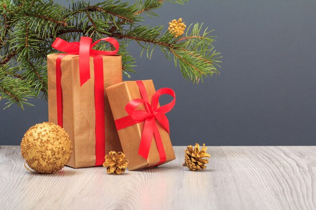 Christmas decoration. Gift boxes, toy ball and fir tree branch on gray background. Christmas greeting card concept.