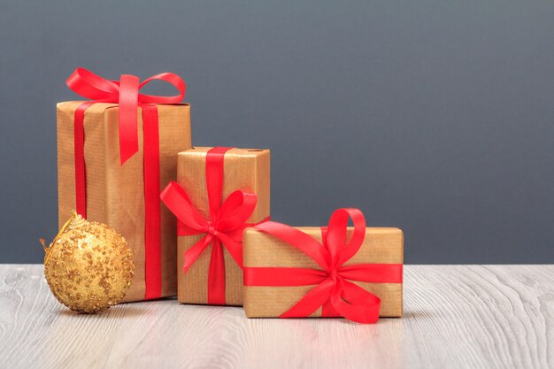 Christmas decoration. Gift boxes and toy ball on wooden boards and gray background. Christmas greeting card concept.