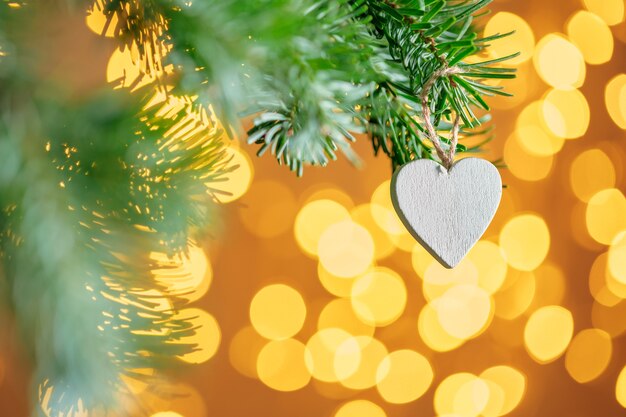 Christmas decoration hanging on a fir tree branch against christmas lights