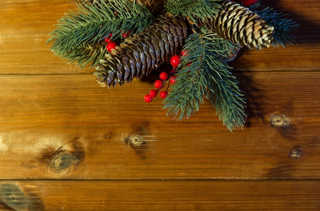 크리스마스 장식, 휴일, 새해 및 장식 개념 - 나무 테이블에 있는 천연 전나무 가지와 전나무 콘을 닫습니다.