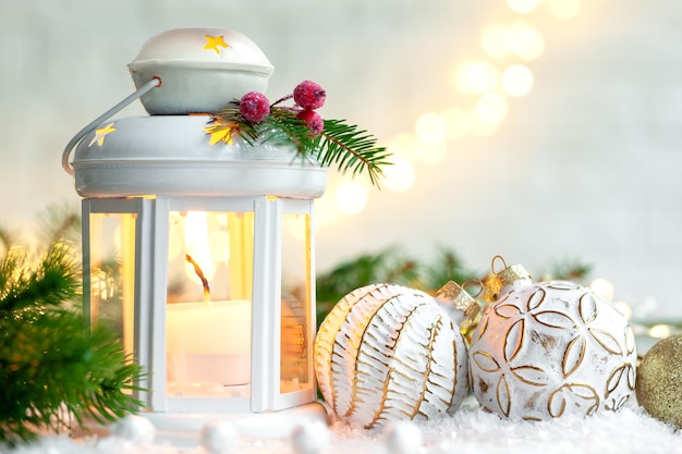 Christmas decoration lantern with burning candle and cristmas balls on light festive background.
