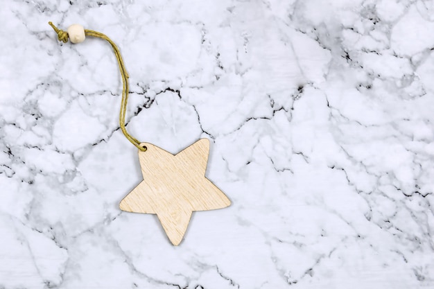 Christmas decoration on a marble background. Wooden star, minimalism, flat lay, eco style.