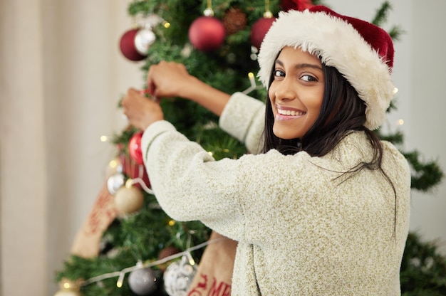 Foto decorazione natalizia o ritratto di donna felice con albero in casa durante la preparazione delle vacanze in vacanza faccina sorridente o donna indiana che appendono ornamenti o decorazioni per la celebrazione festiva in casa