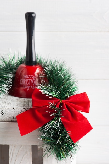 Christmas decoration in Scandinavian white interior with red bow, bell and lit candle. Copy space for greeting