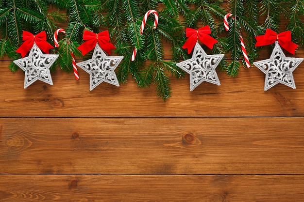 크리스마스 장식, 별, 화환 프레임 개념 배경, 소박한 나무 테이블 표면에 복사 공간이 있는 위쪽 전망. 전나무 나무 가지와 새해 장식품 테두리
