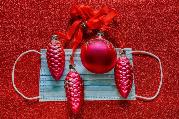 Christmas decoration with blue medicine face mask and red festive garland on red background