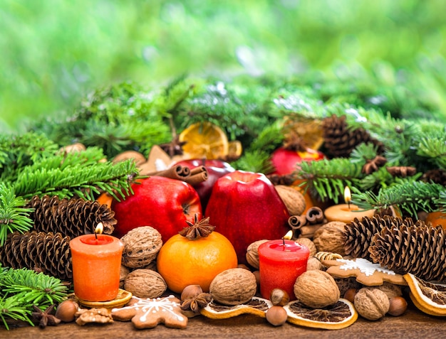 Christmas decoration with candles, cookies, fruits, nuts and spices