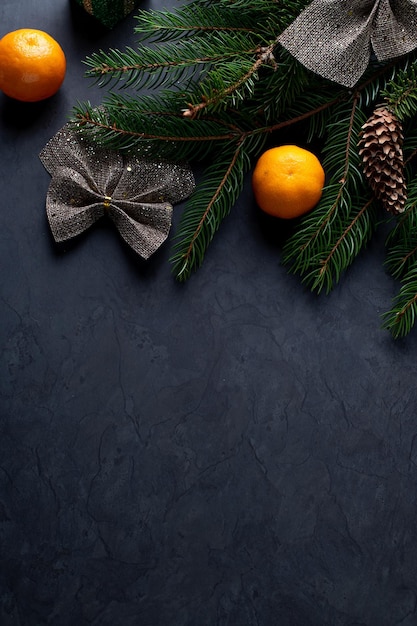 モミの枝の円錐形と垂直方向の暗い背景にみかんとクリスマスの装飾
