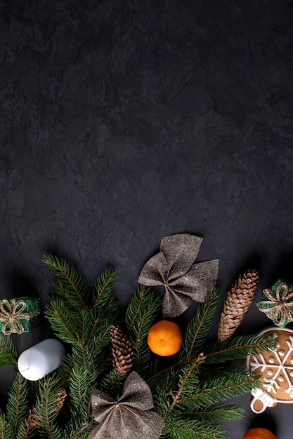 Christmas decoration with fir branches cones and tangerines on a dark background vertical