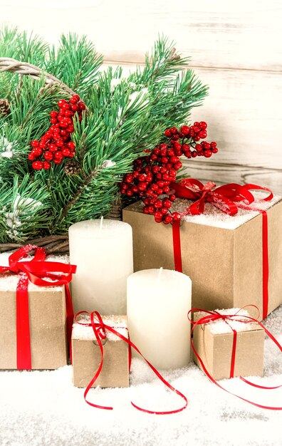 Christmas decoration with white candles, gift boxes and pine tree branches. Vintage style toned photo