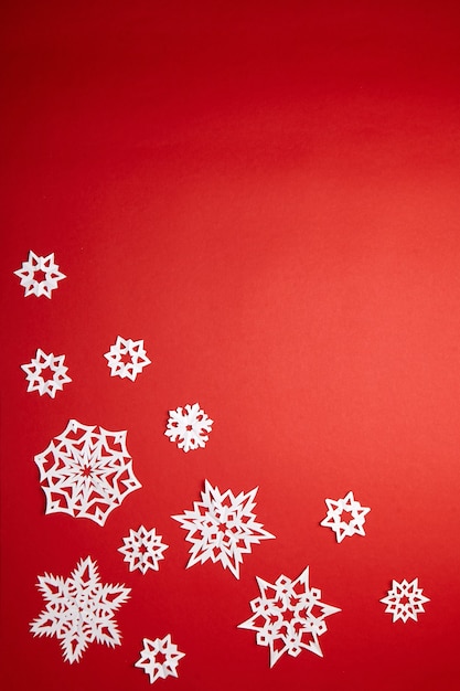 Christmas decoration with white snowflakes on red background flat lay