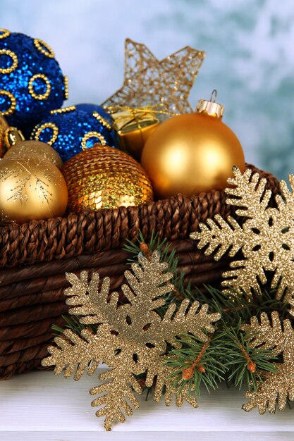 Christmas decorations in basket and spruce branches on table on bright background