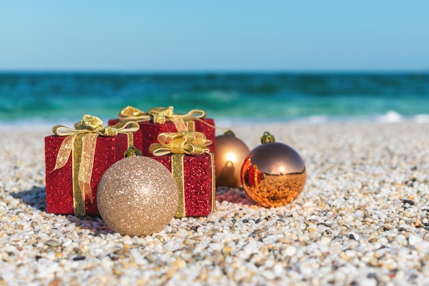 Christmas decorations and baubles in the sand on a beach