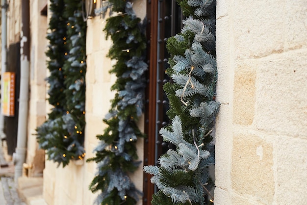 Christmas Decorations Garland Lights And Fir Branches On Window Of Cafe In European City Street