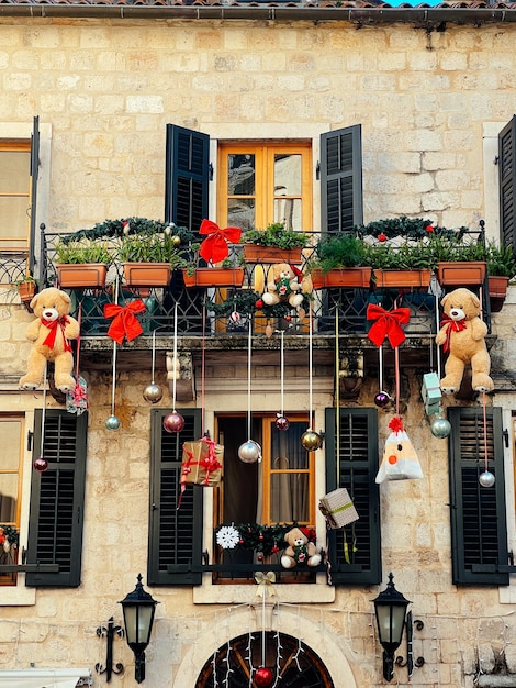 Christmas decorations hang from the balcony of an old stone house