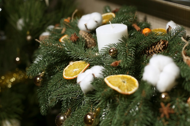 Decorazioni natalizie fatte di albero di natale artificiale, batuffoli di cotone, coni, fette d'arancia e bastoncini di cannella