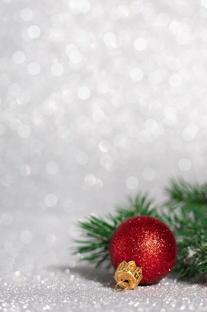 Christmas decorations made of red ball with tree branches on blurred glitter background, copy space