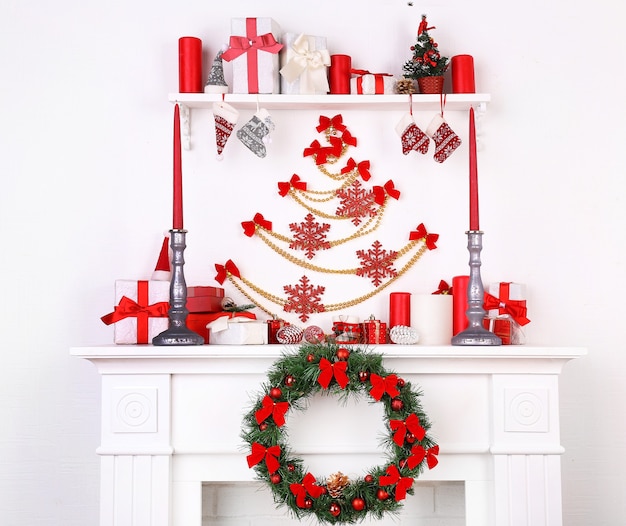 Christmas decorations on mantelpiece on white wall surface