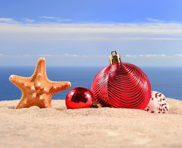 Decorazioni natalizie, conchiglie e stelle marine su una spiaggia di sabbia sullo sfondo del mare