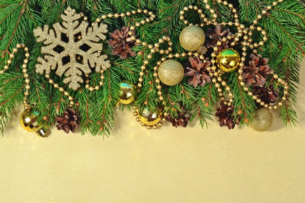 Christmas decorations and spruce branch and cones on a golden background