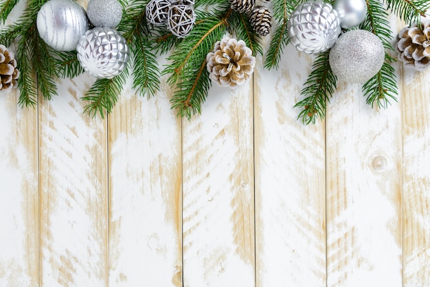 Christmas decorations, white balls and pine cones on a white wooden table. Top view, copy space.