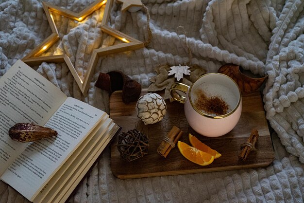 Foto decorazioni natalizie con luci, bevande calde, frutta e un buon libro.