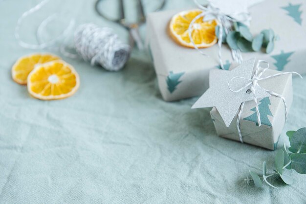 Photo christmas  decorative homemade gift boxes wrapped in brown kraft paper on a green textile background