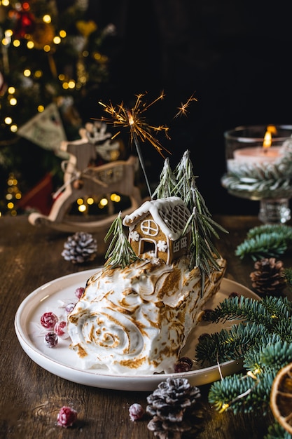 Photo christmas dessert, meringue roll decorated with gingerbread house