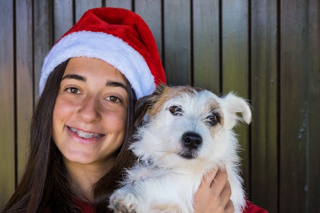 女の子とクリスマスの犬。幸せな瞬間、クリスマスの帽子と笑顔。