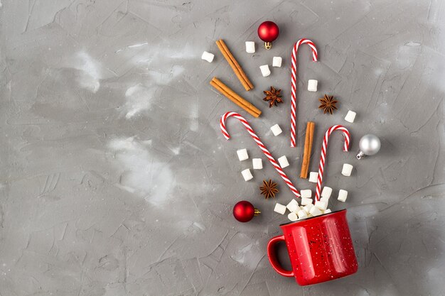 Foto concetto di celebrazione della bevanda di natale. tazza con marshmallow, anice, cannella e bastoncino di zucchero sul tavolo grigio