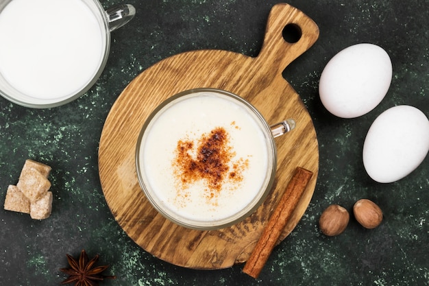 Рождественский напиток eggnog и ингредиенты на зеленом