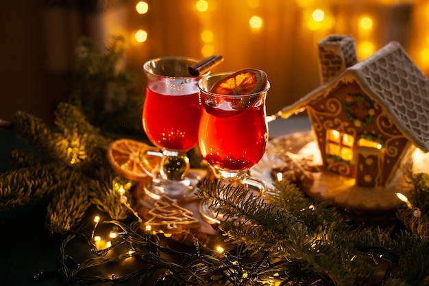 Christmas drink with spicy and berries with gingerbread house and spruce branches