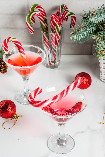 Bevande di natale, rosa martini menta piperita cocktail con decorazioni natalizie e zucchero filato dolce sul tavolo da cucina in marmo bianco, copia spazio