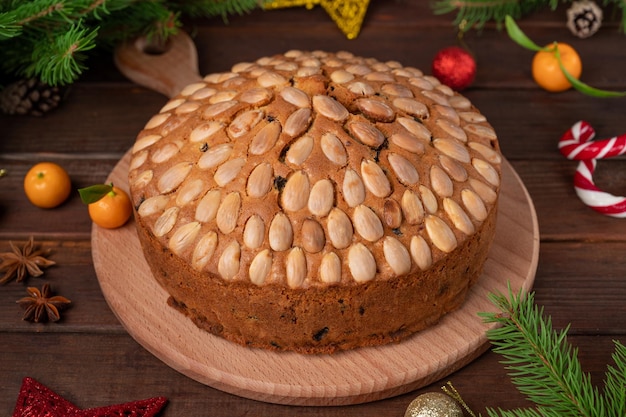 Christmas Dundee cake with dried fruits and almonds on a wooden board selective focus