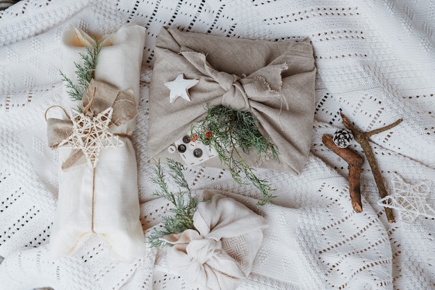 Christmas eco-friendly gift wrap in traditional Japanese furoshiki style on a knitted white wall. Wrapping gifts with your own hands. Cheap new year.