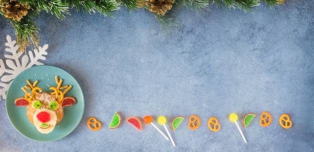 Christmas edible deer of buns and marmalade on holiday table next to candy snowflakes