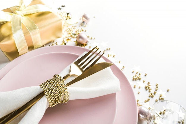 Christmas elegance table setting with pink dishware, golden silverware on