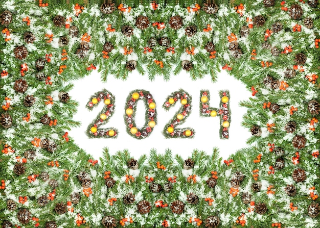 사진 크리스마스 이브 배경과 2024 번호는 하 배경에 고립 된 크리스마스 트리 가지로 만들어졌습니다.